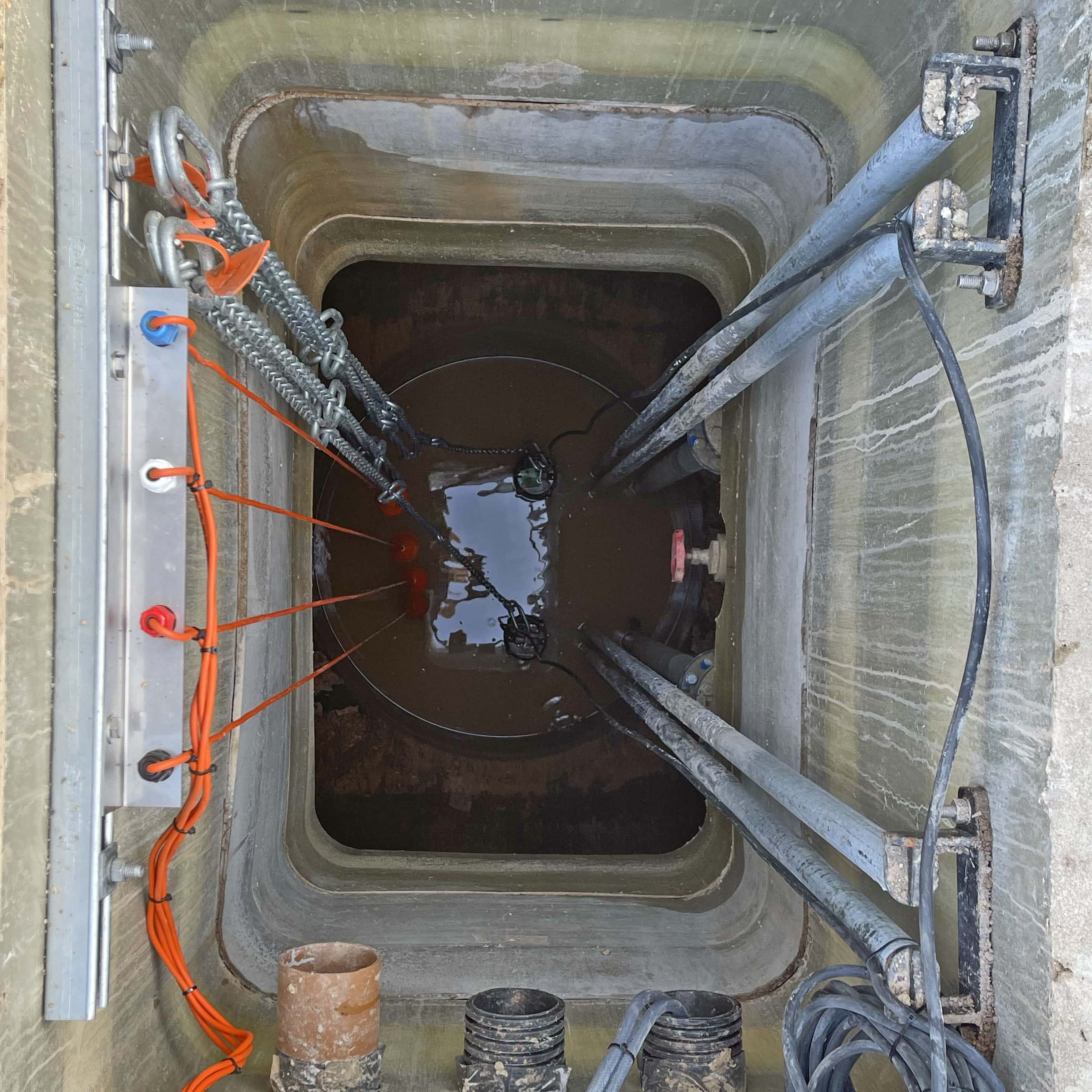 Inside view of a manhole with water and cables.
