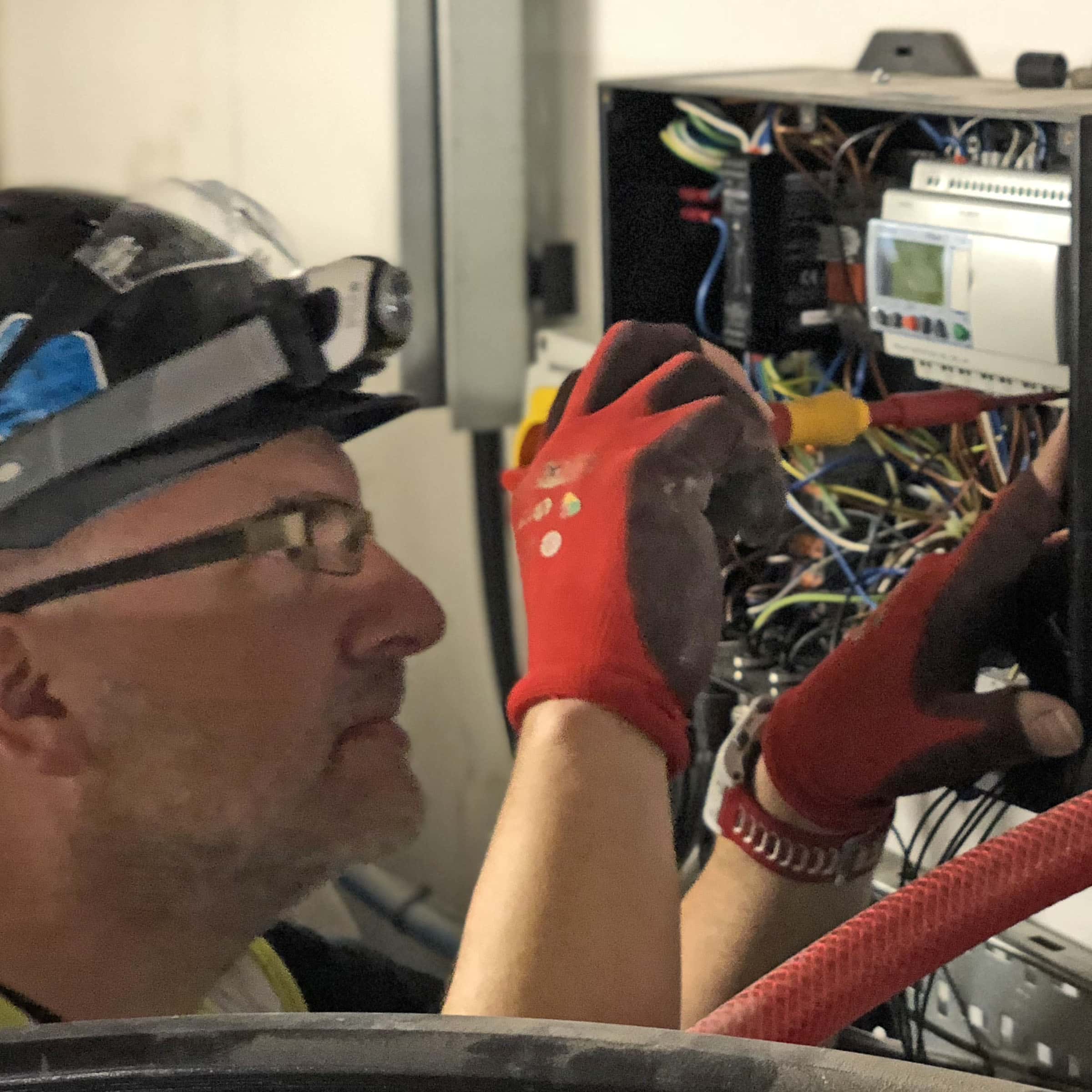 Electrician working on circuit board with tools