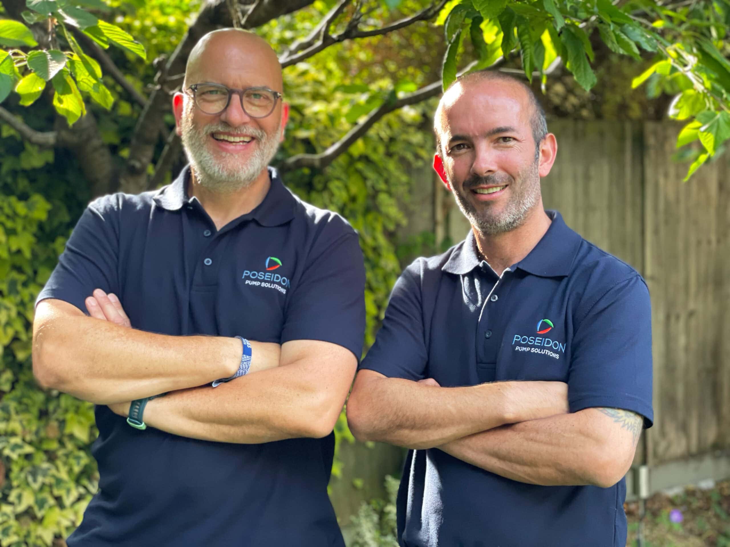 Two men smiling in Poseidon Pump shirts outdoors.